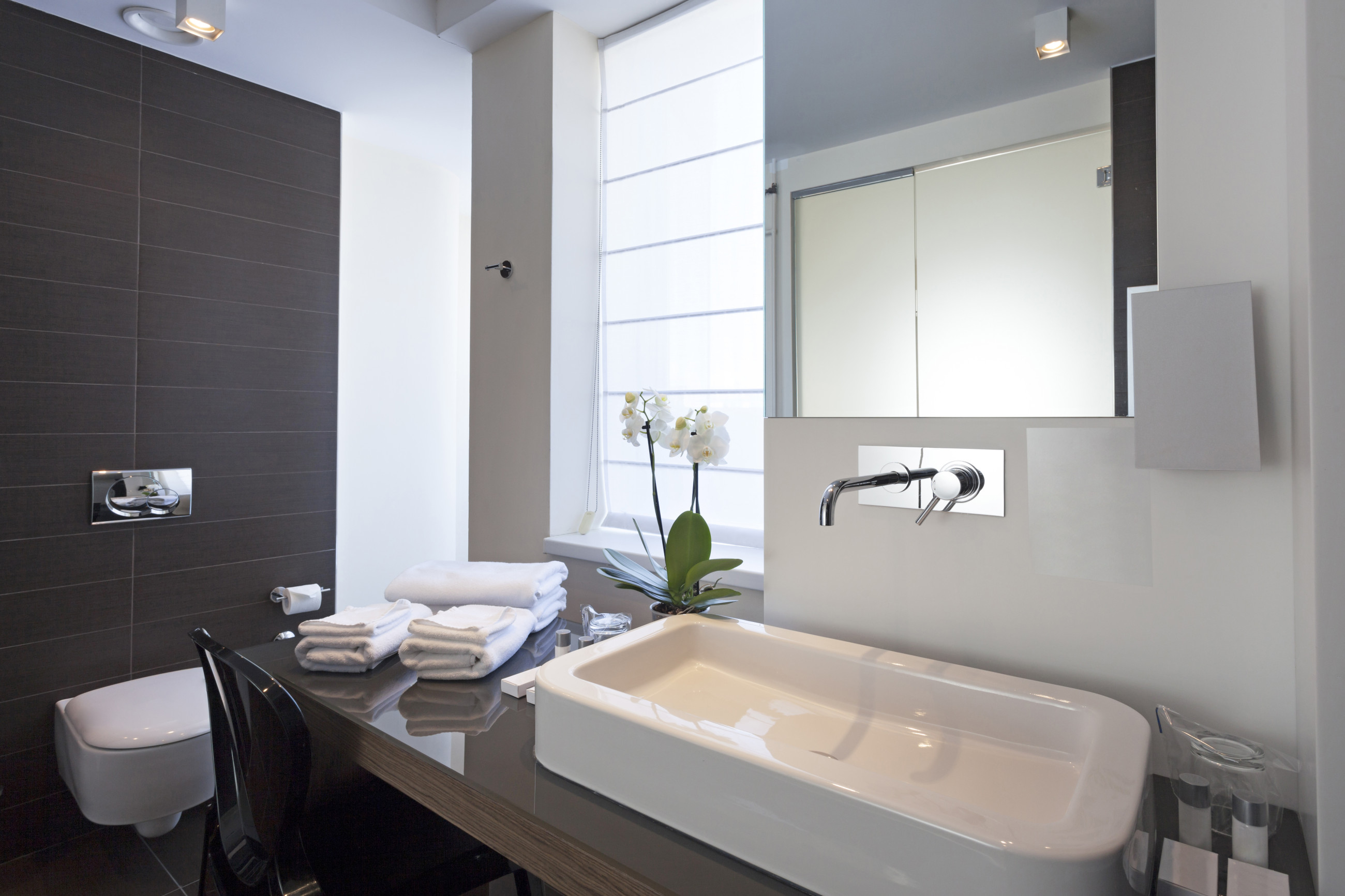 Elegant modern bathroom mirror in dark grey tiled bathroom