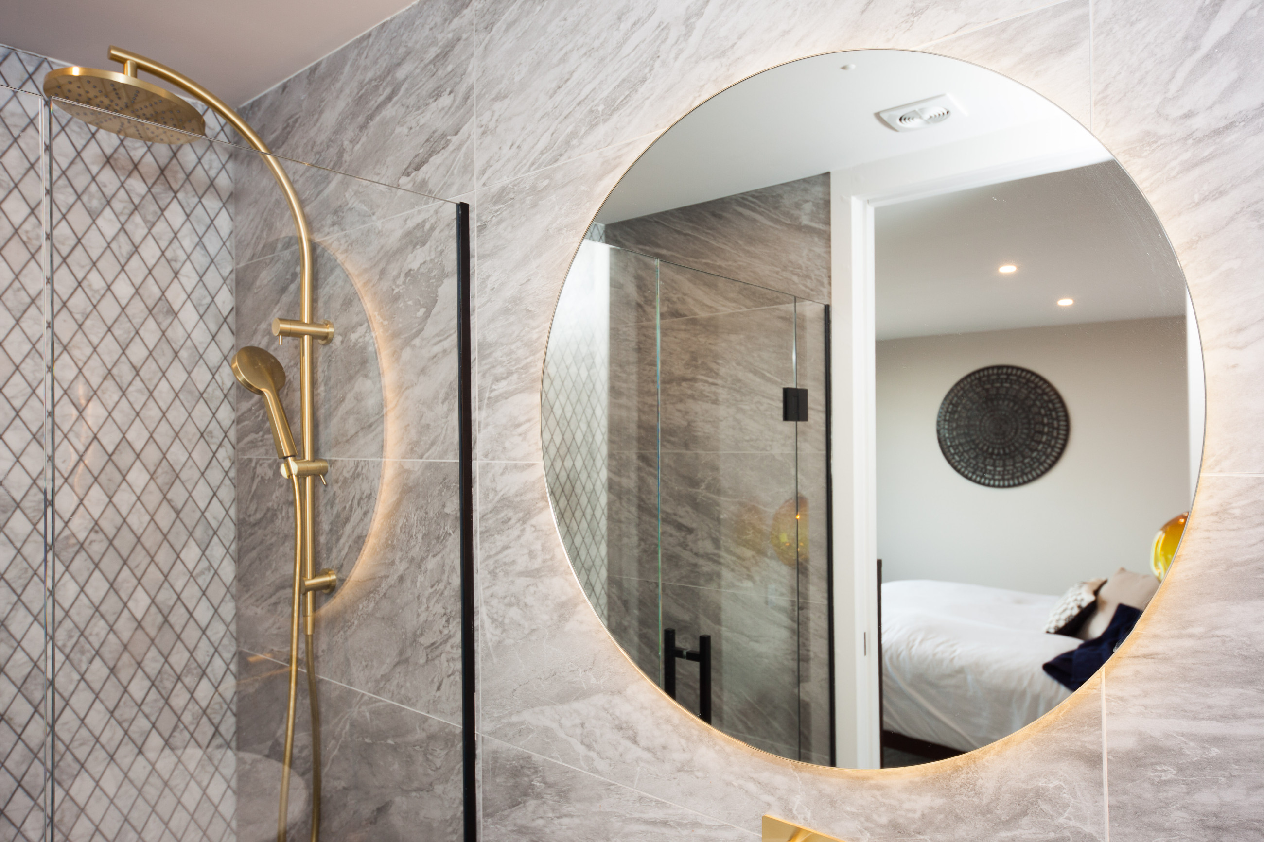Elegant modern bathroom mirror in patterned bathroom with gold features