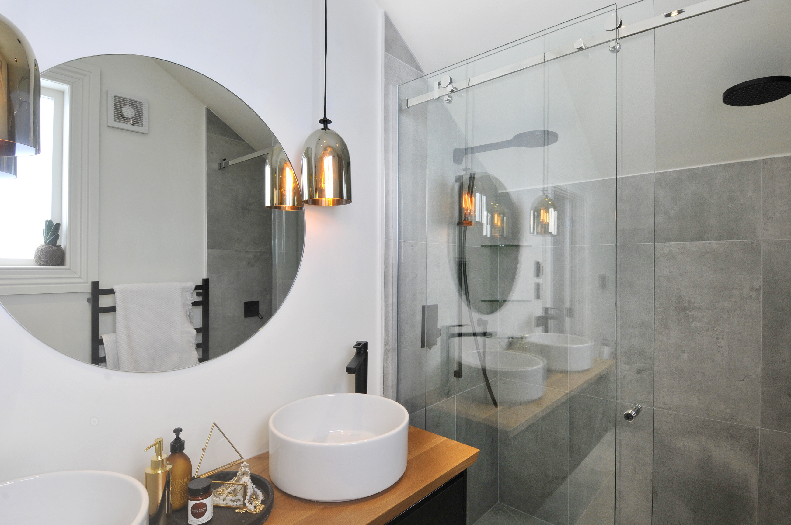 Elegant modern bathroom mirror in grey tiled bathroom