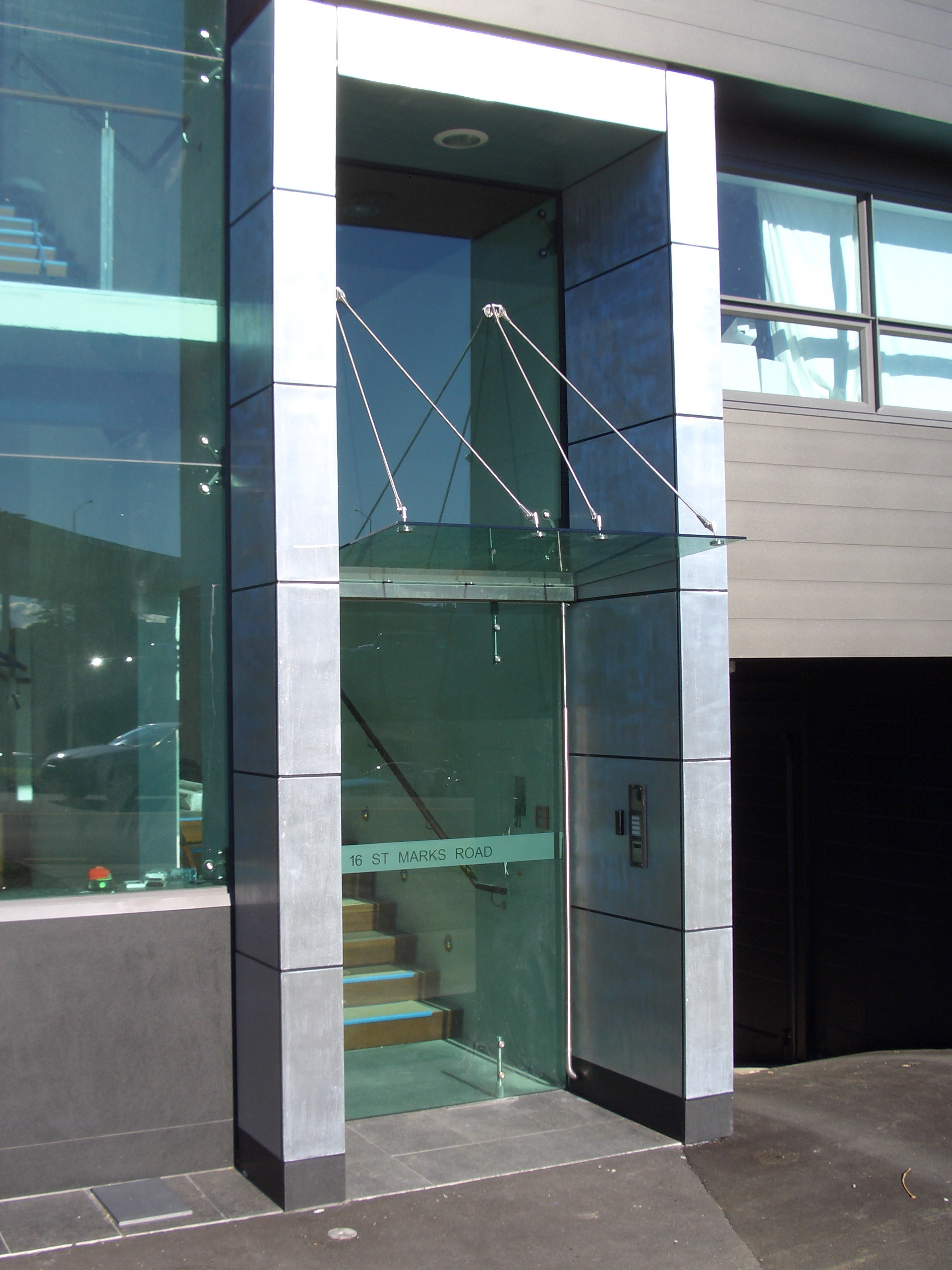 Grey architectural building adorned with a sleek glass canopy