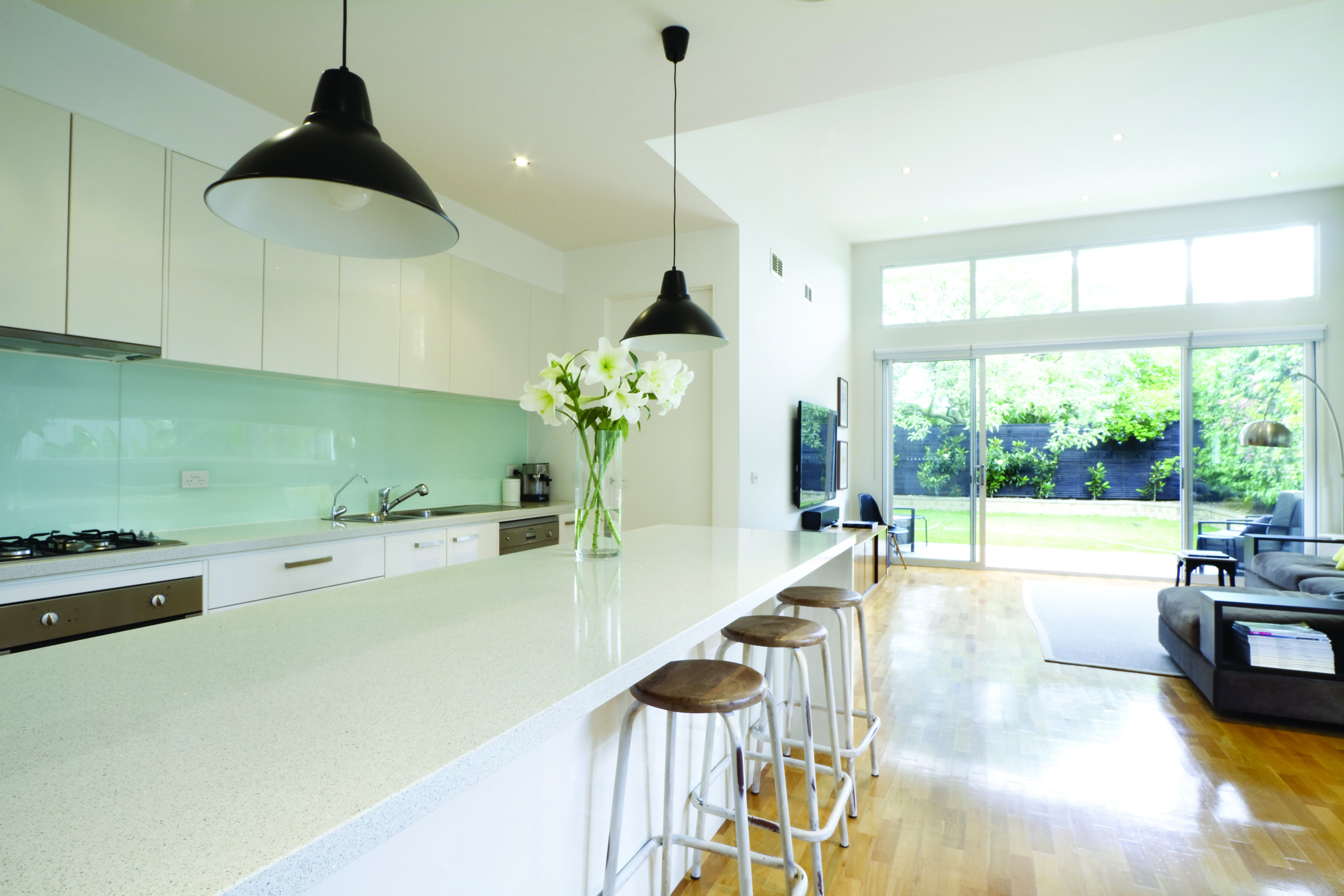 White kitchen with light green splash back, in living room