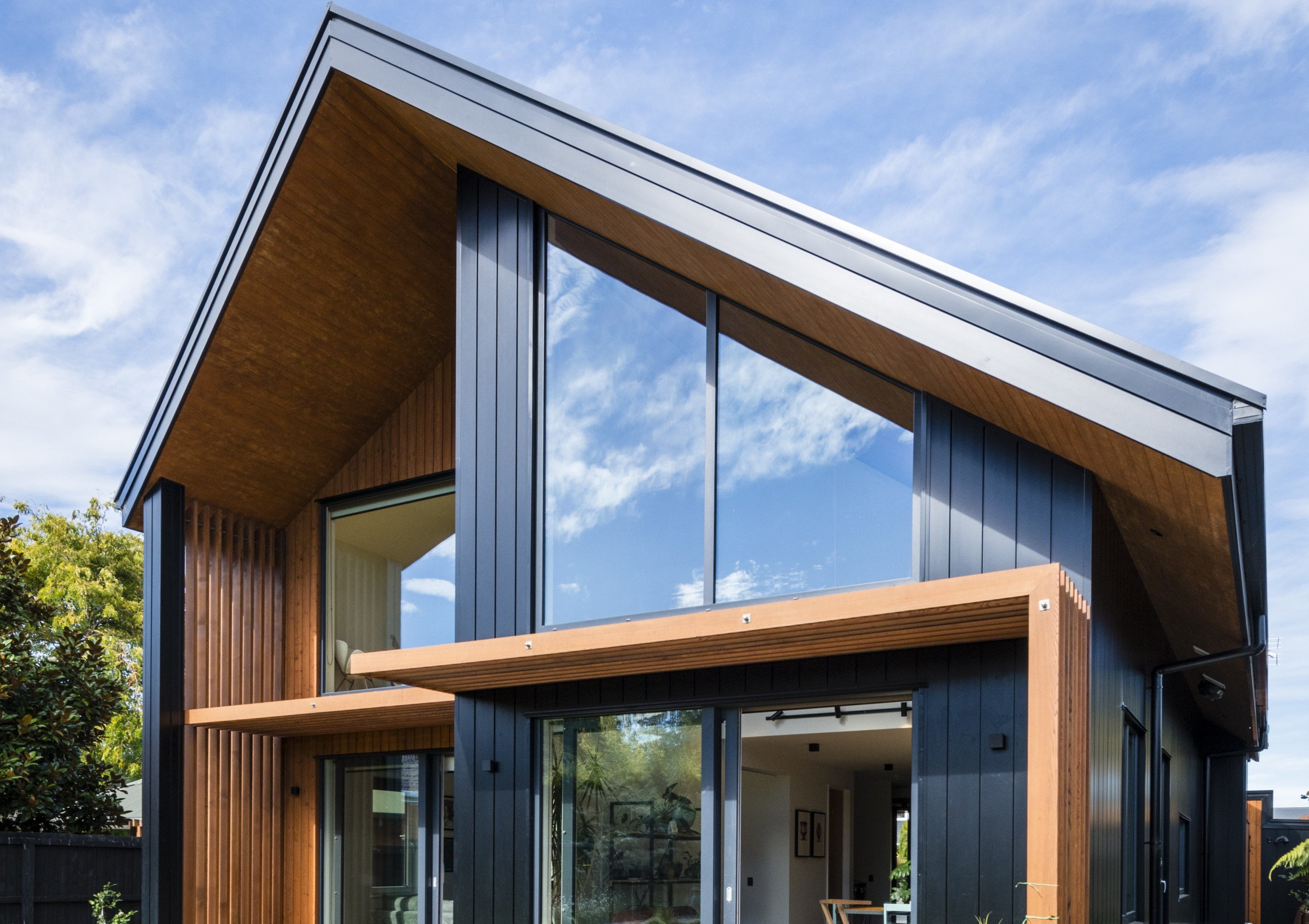 Architectural detail of a modern home with large glass panes and wood accents under a clear sky