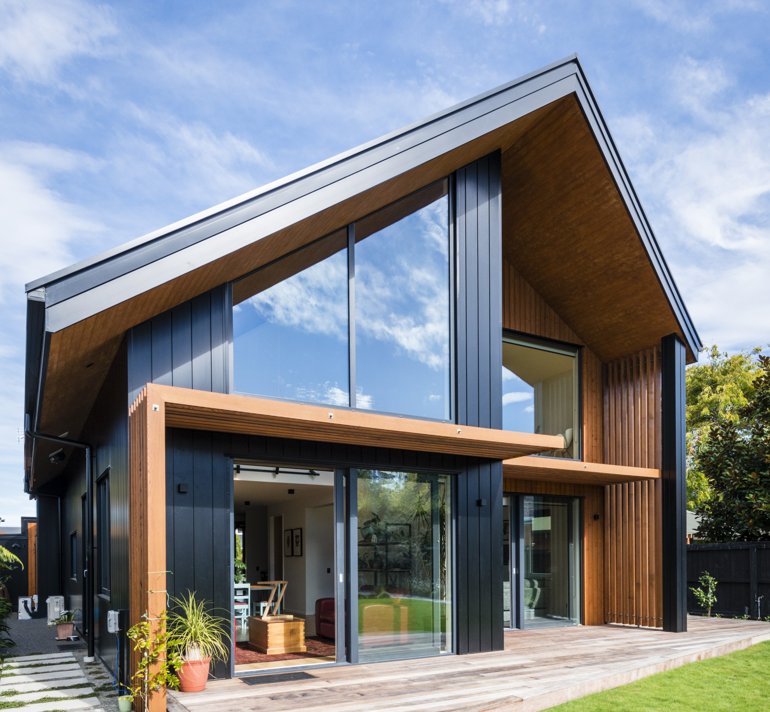 Modern angular home with reflective glass and wooden exterior detailing