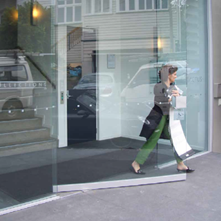 Lady walking into sleek glass entry doors leading into a modern commercial space