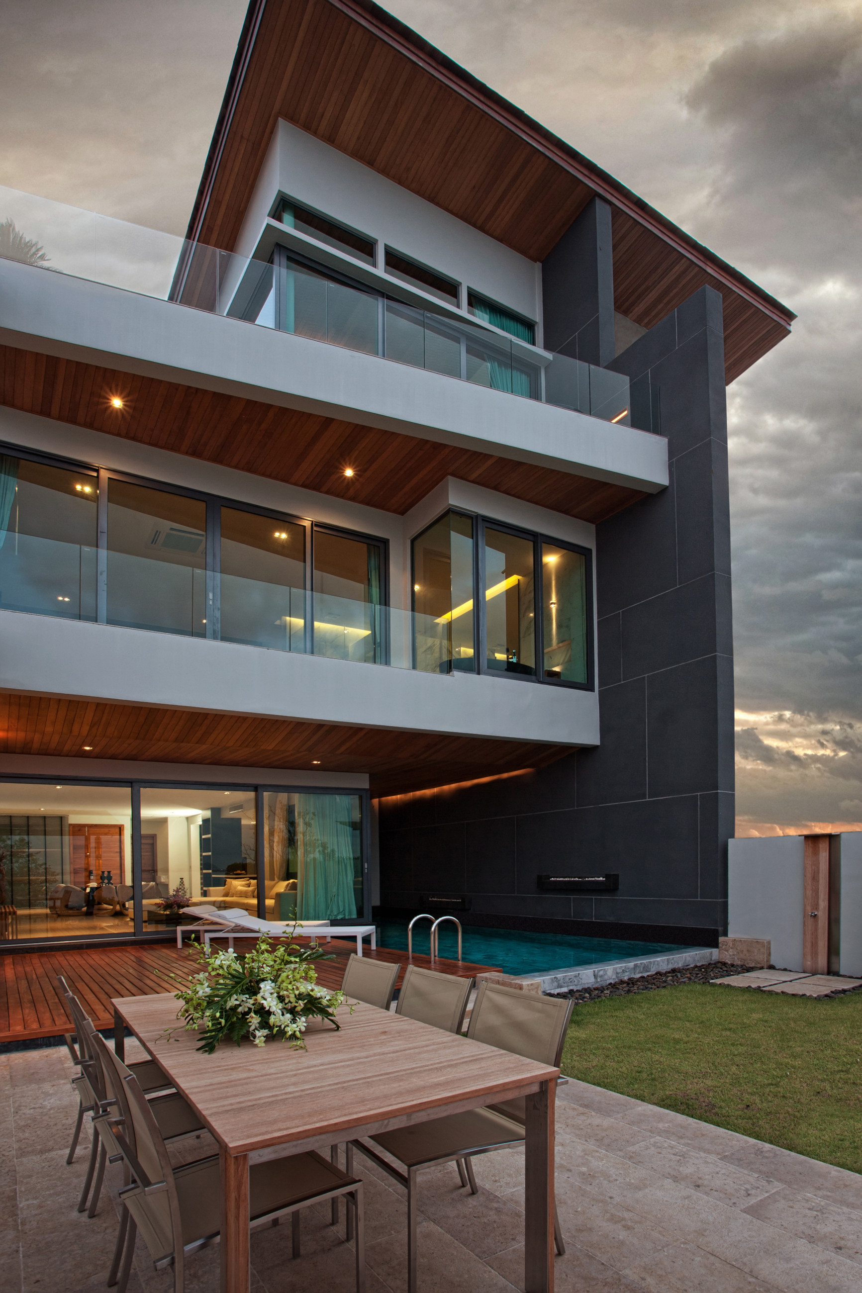 Modern house featuring a glass balustrade, swimming pool, and outdoor seating area