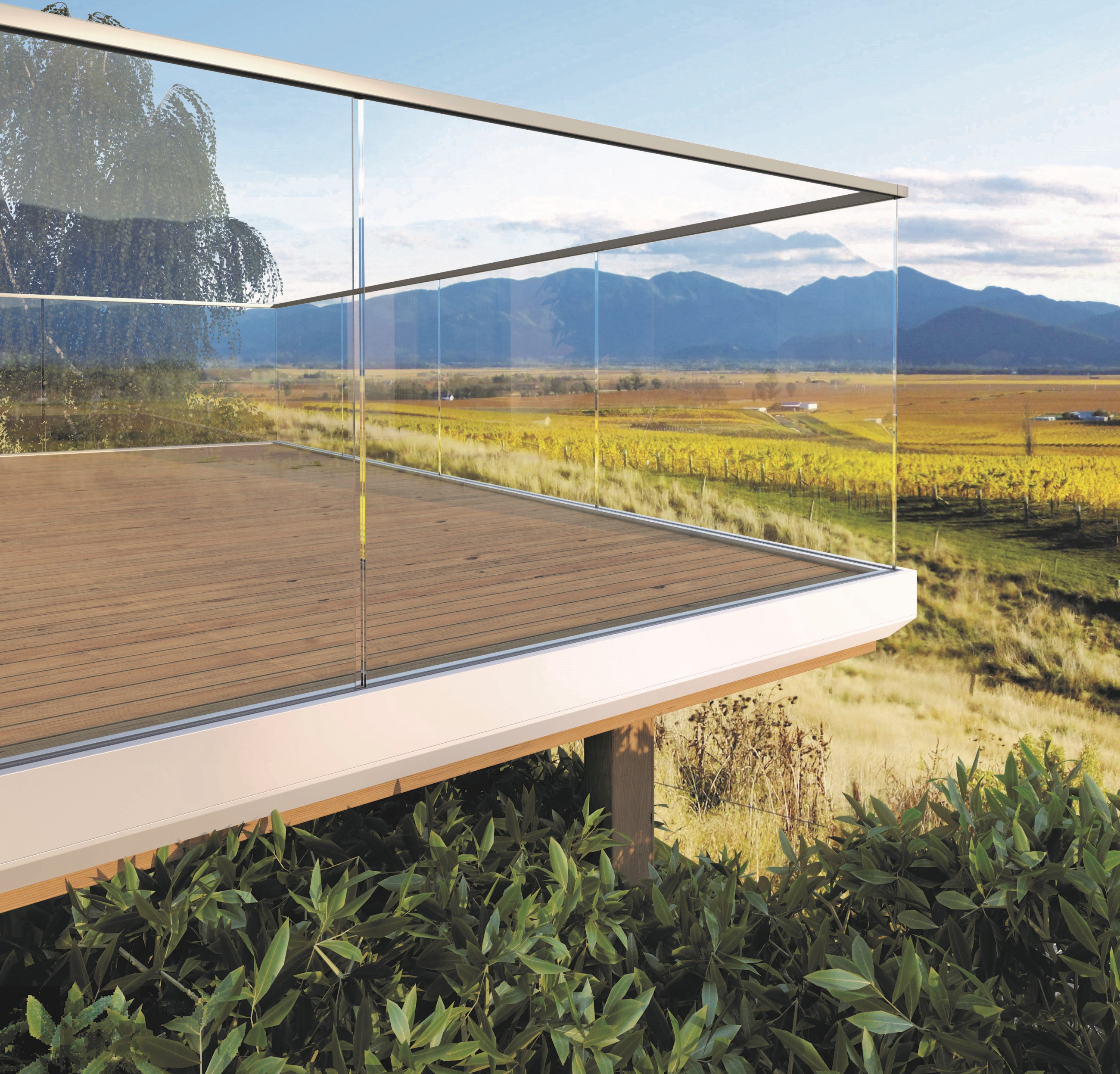 Glass balustrade overlooking a lush green farm and distant mountain scenery