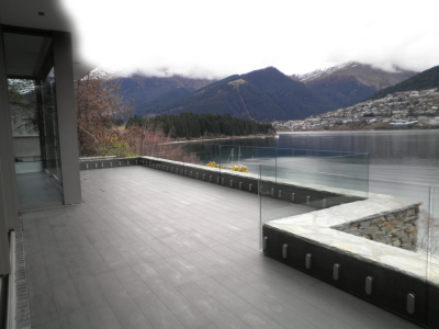 Dark decking with a glass balustrade providing expansive views of the ocean and mountains