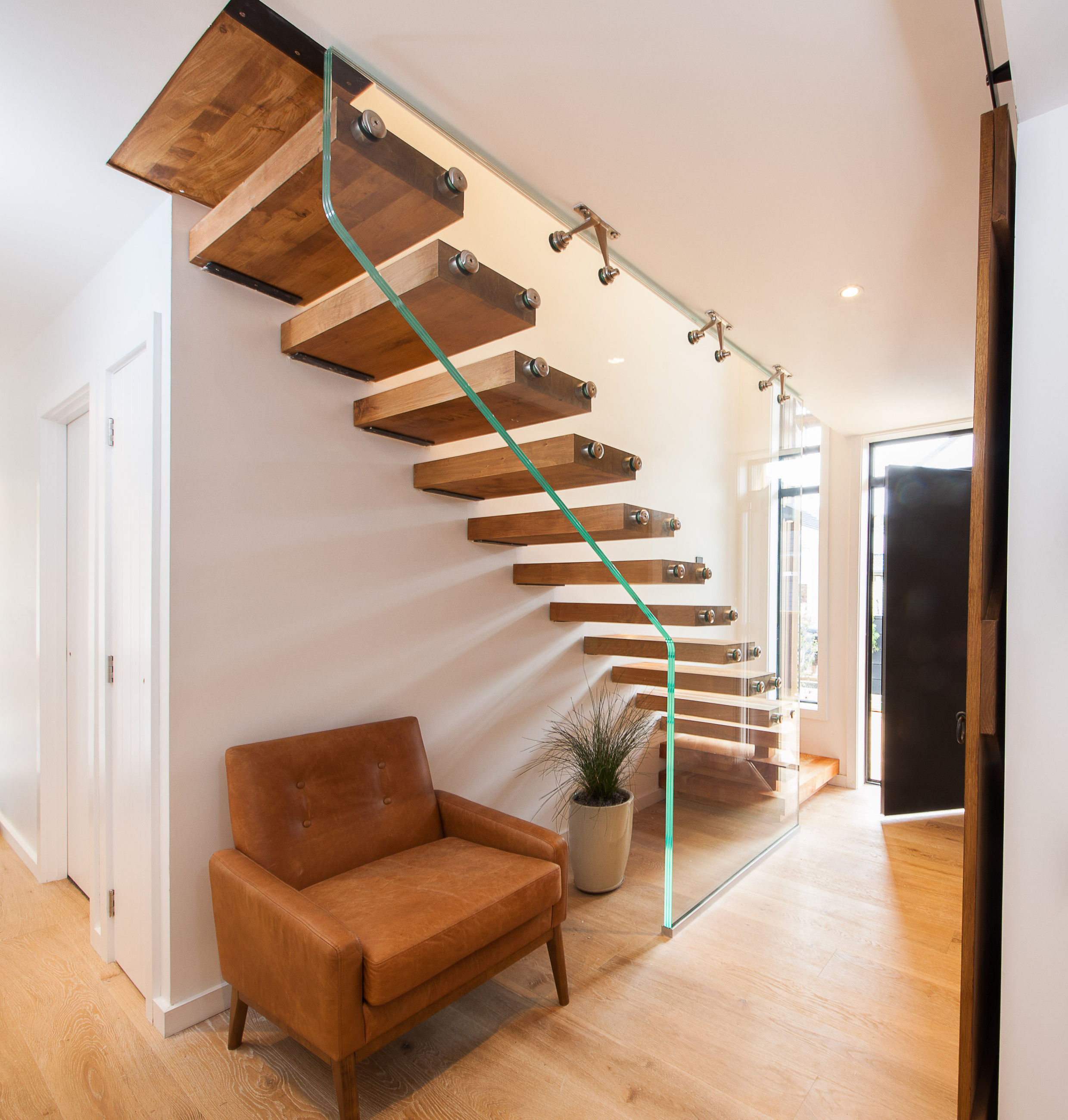 Glass balustrade with wooden stair and leather chair