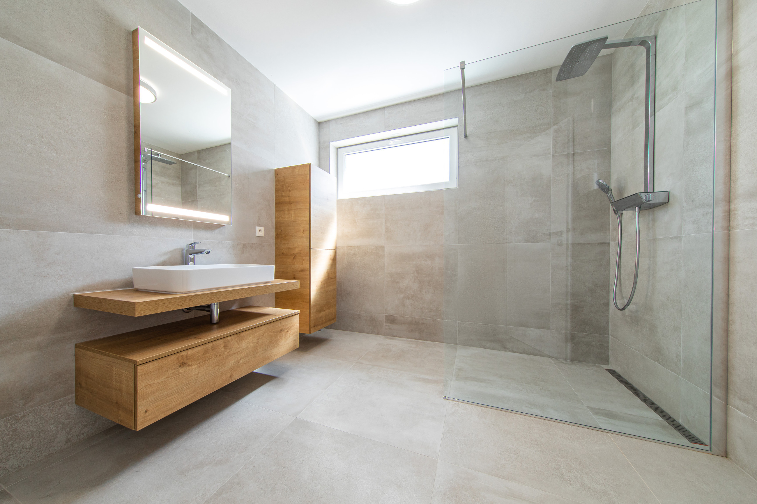 Glass shower screen with a bathtub, basin and cream tiles