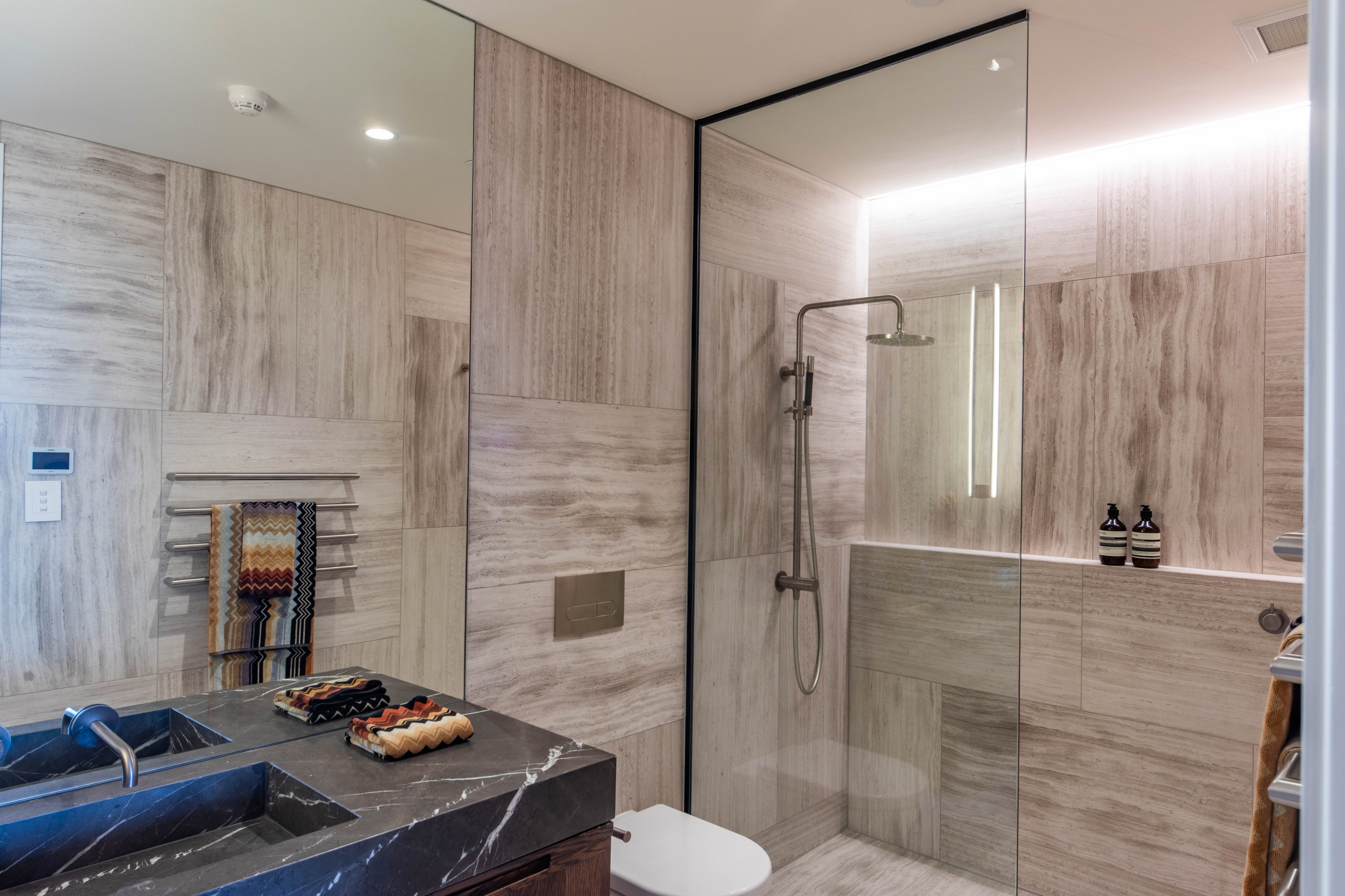 Glass shower screen with a bathtub, basin and patterned tiles