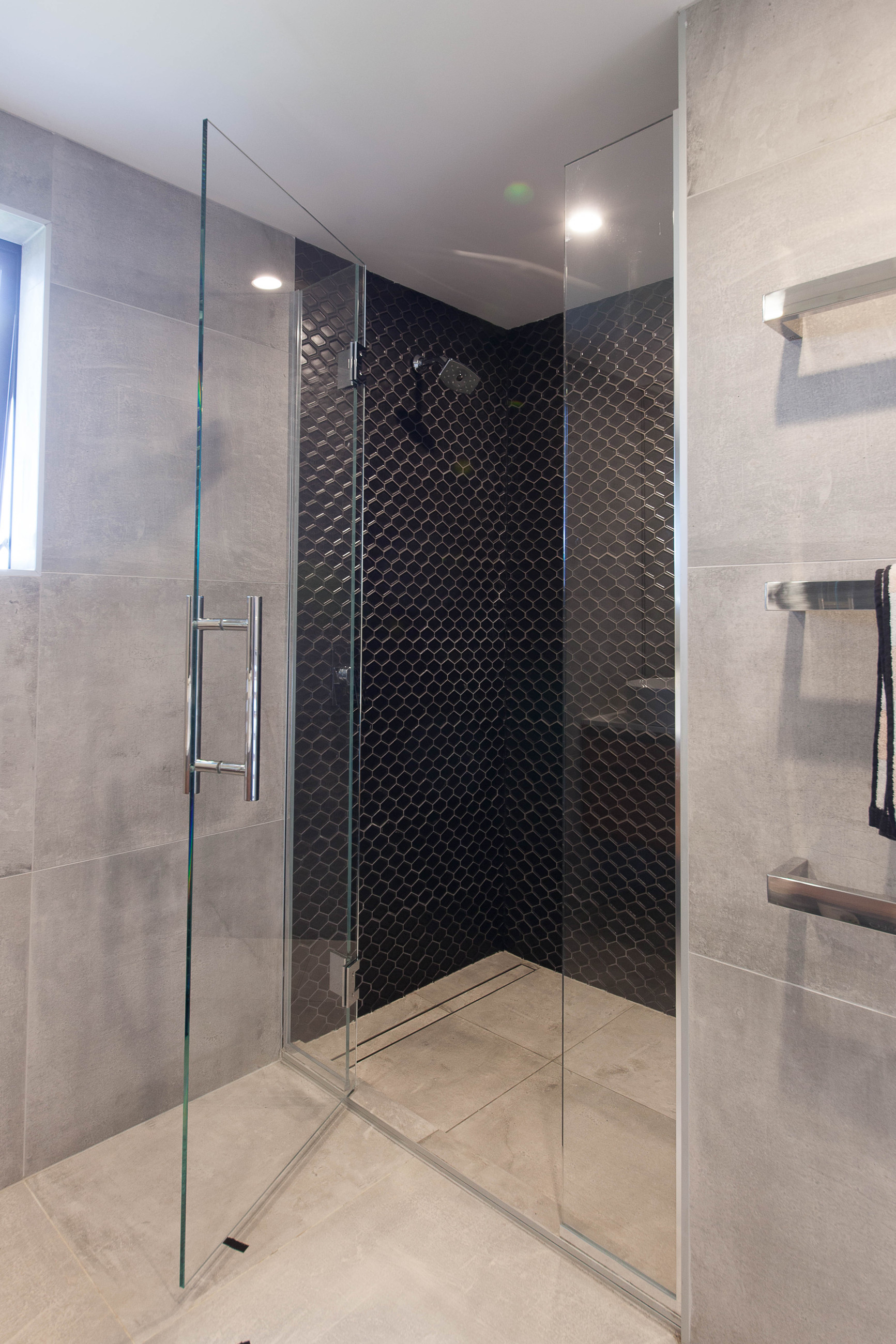 corner shower in bathroom with featuring grey and white tiles