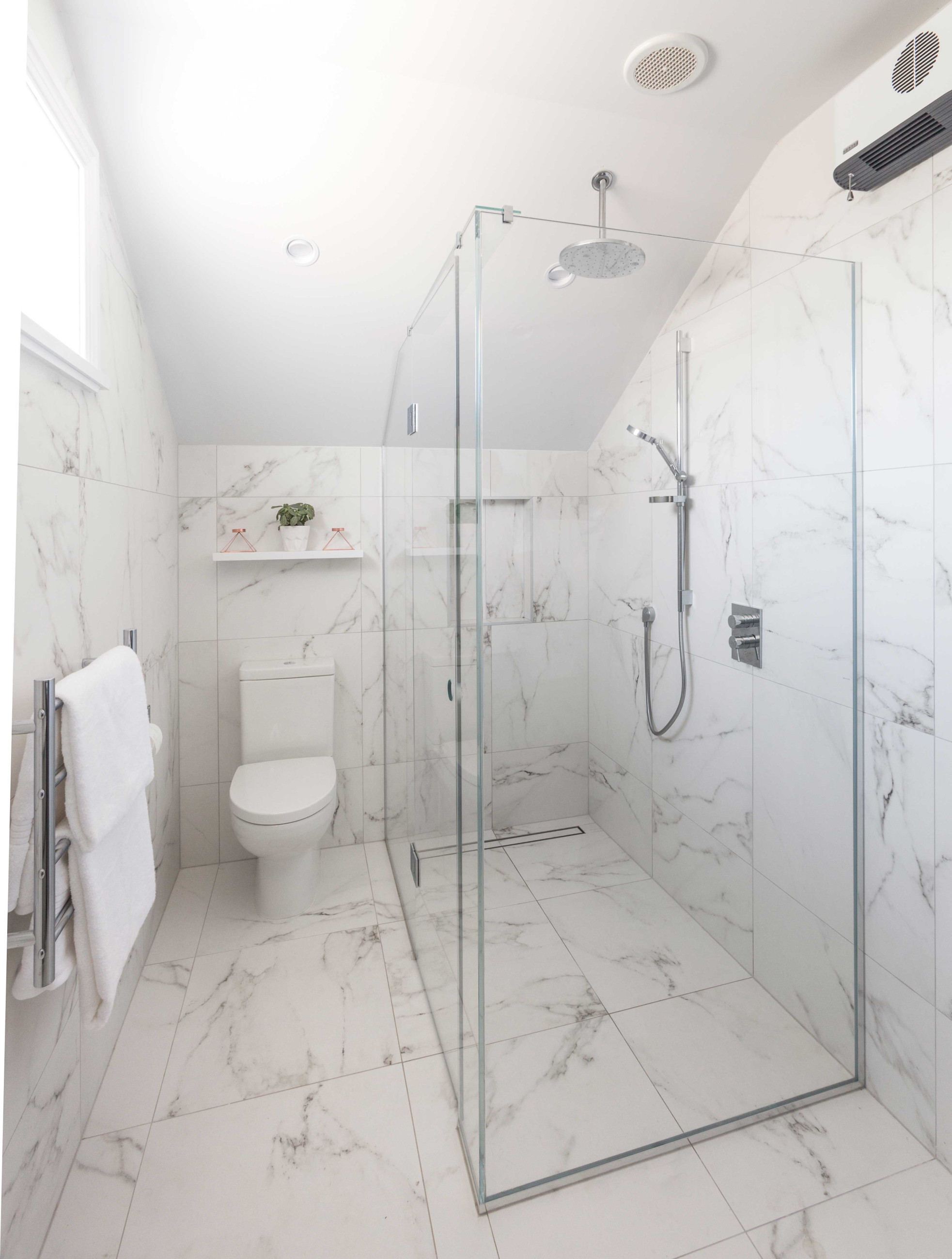 corner shower in bathroom with white marbled tiles