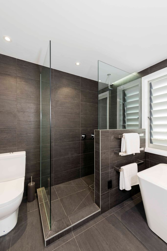 corner shower in bathroom with dark grey tiles