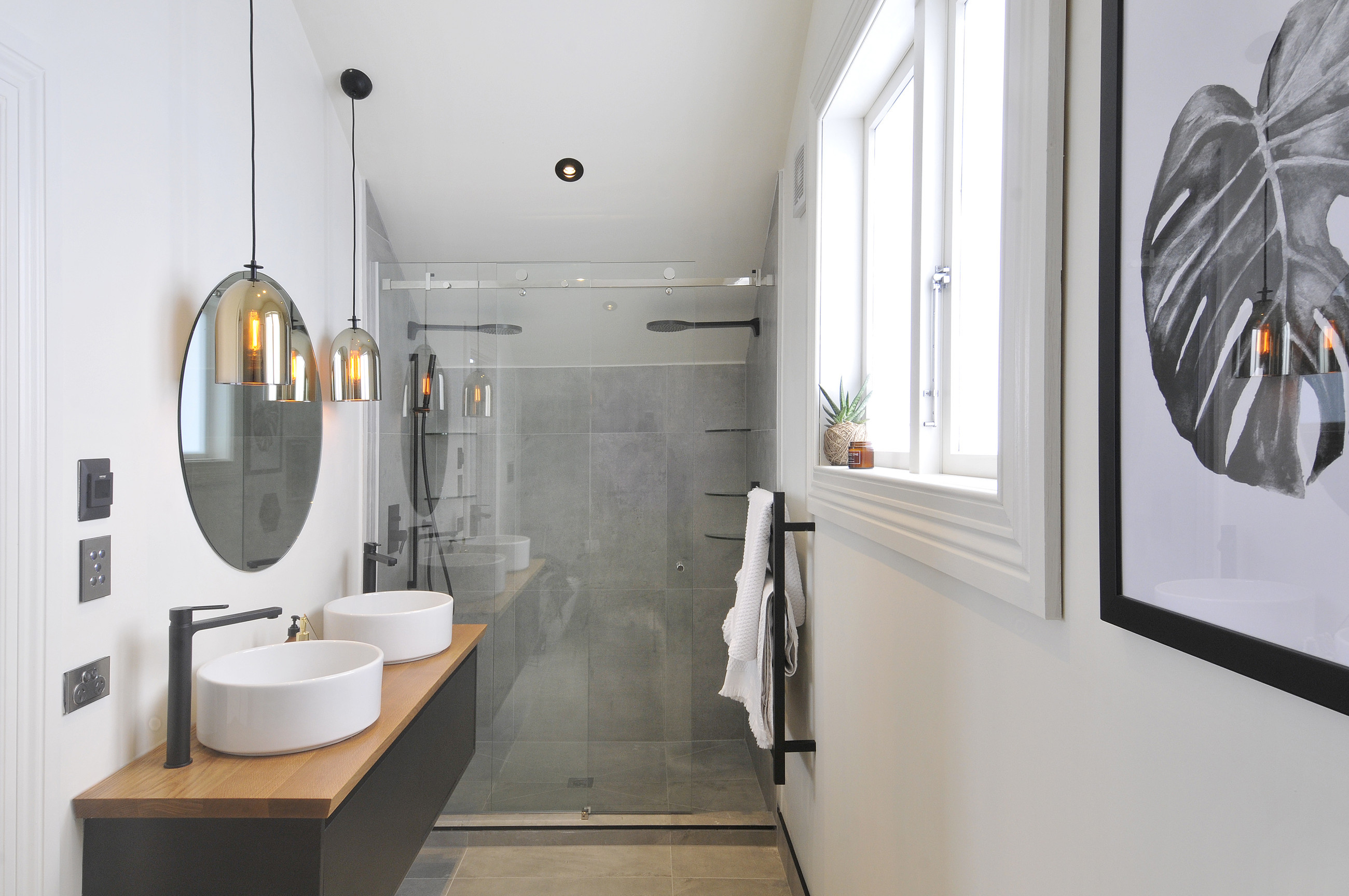 Modern bathroom with a transparent glass shower screen, bath, basin, and white wall