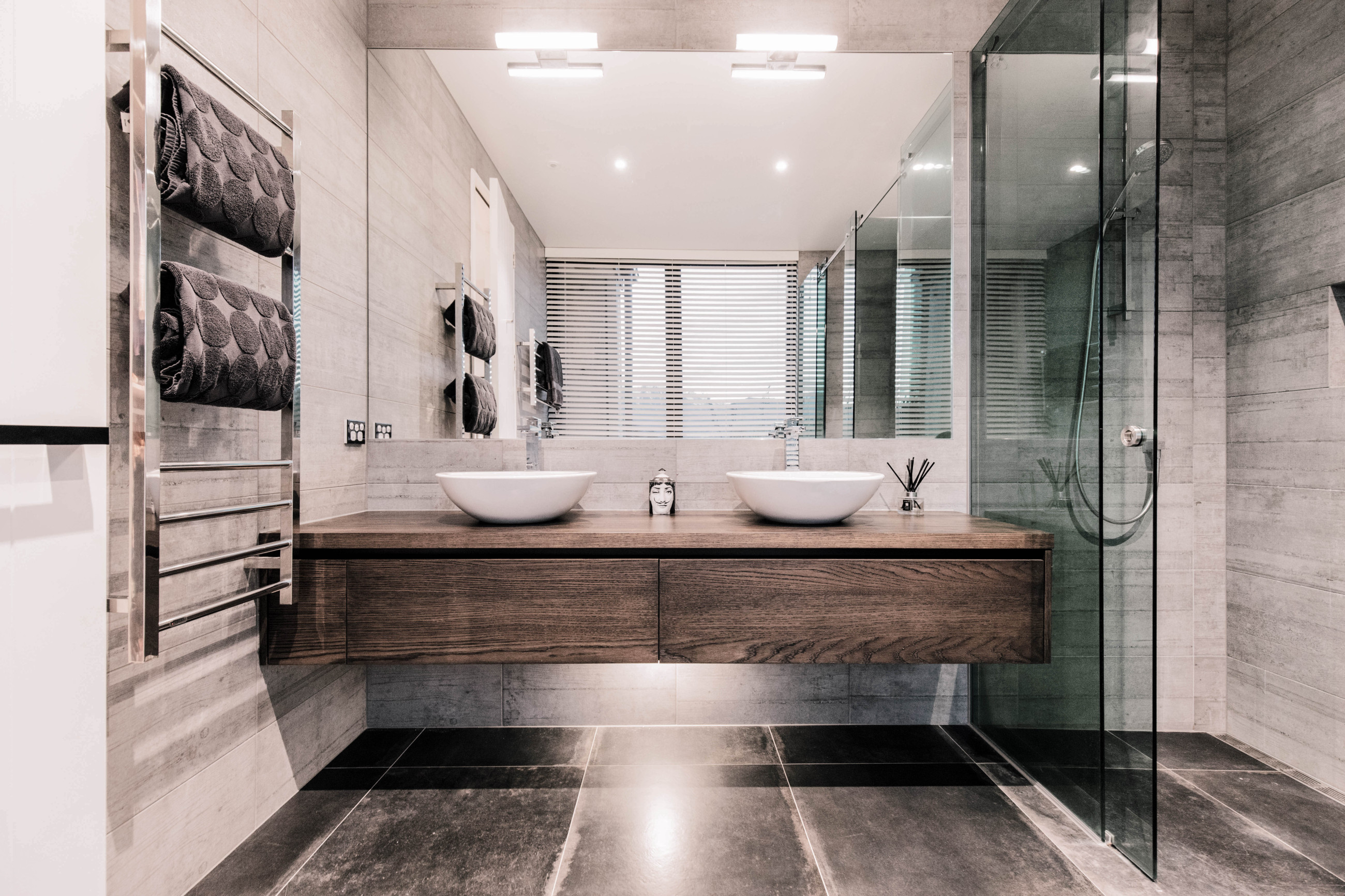 Modern bathroom with a transparent glass shower screen, bath, basin, and a feature wall of marbled tiles