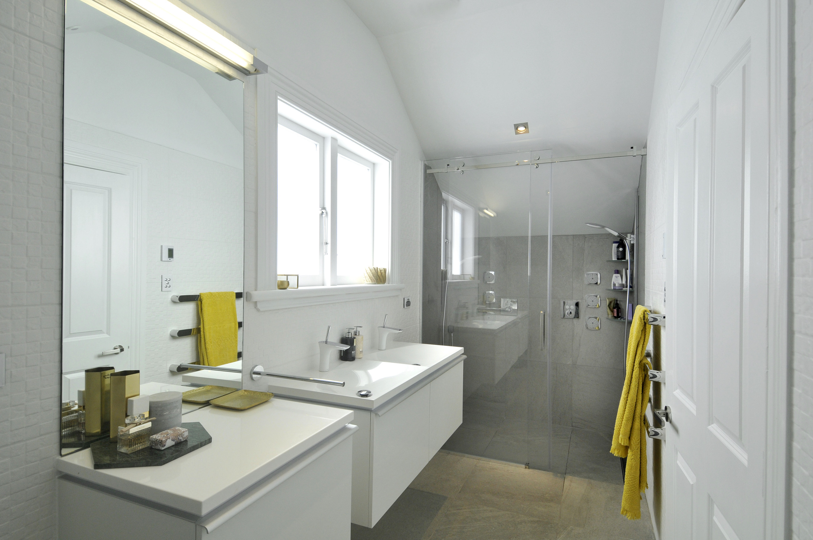 Modern bathroom with a glass shower screen, showerhead, basin, and grey and white tiled walls