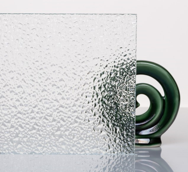 Cropped images of textured etched glass with a stunning glass koru design in the background.