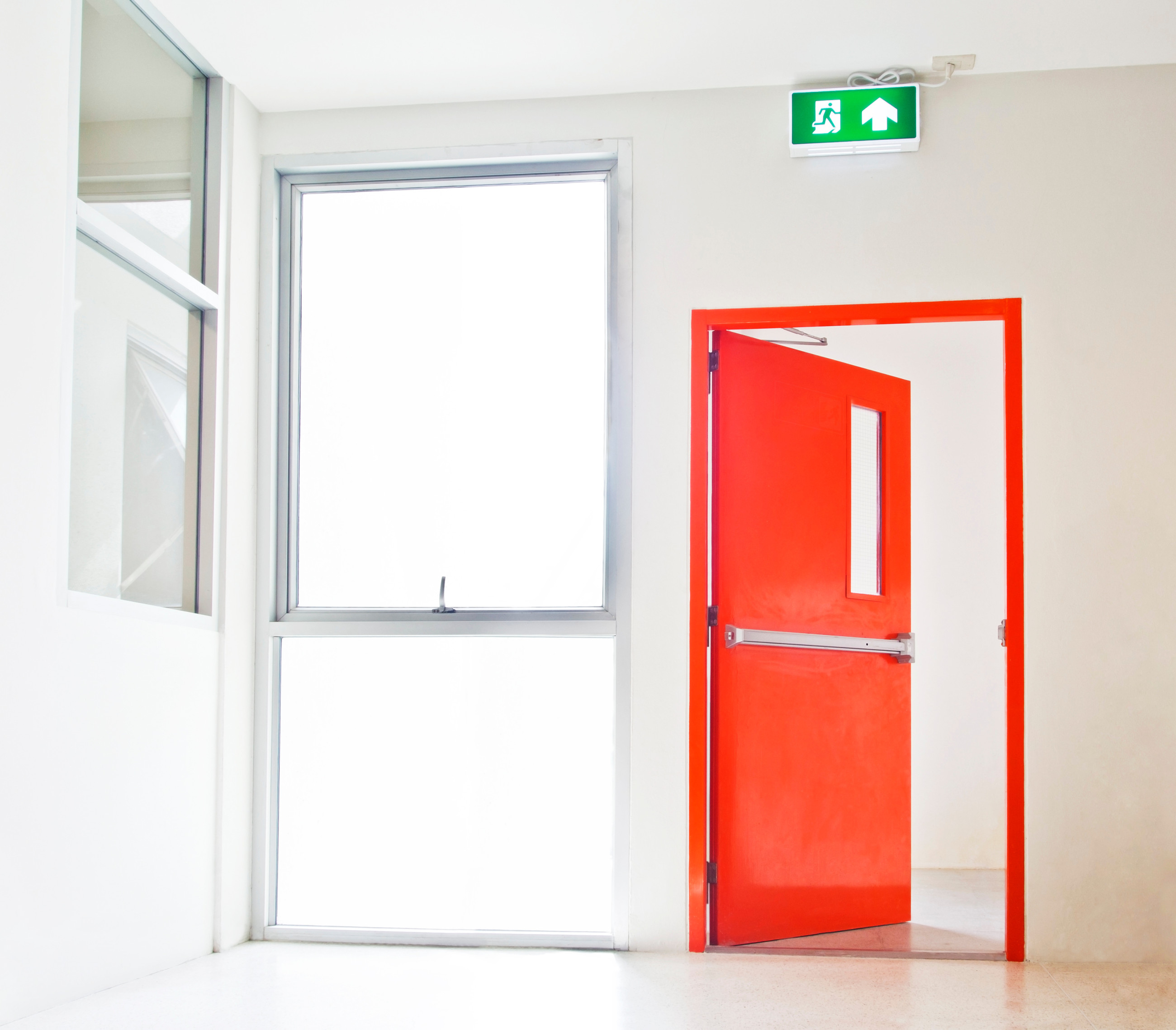 Red fire exit door beside glass windows