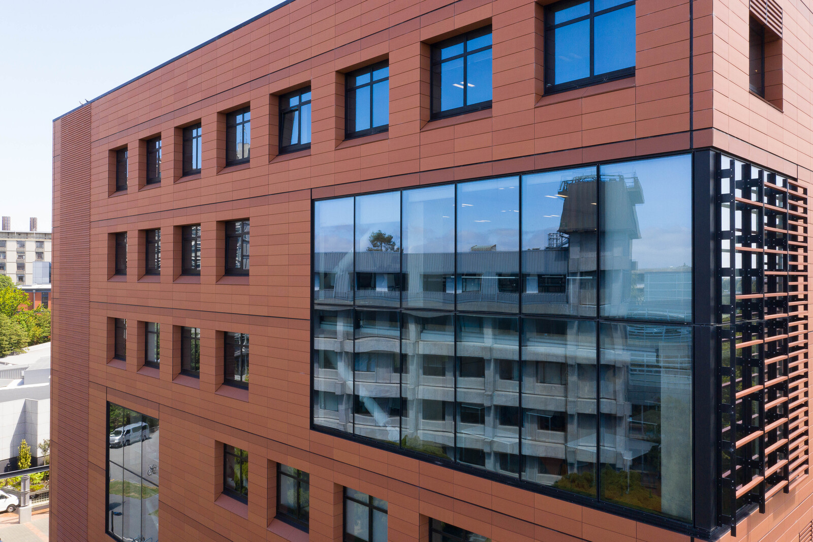 Glass-windowed corner of a modern urban building with red façade