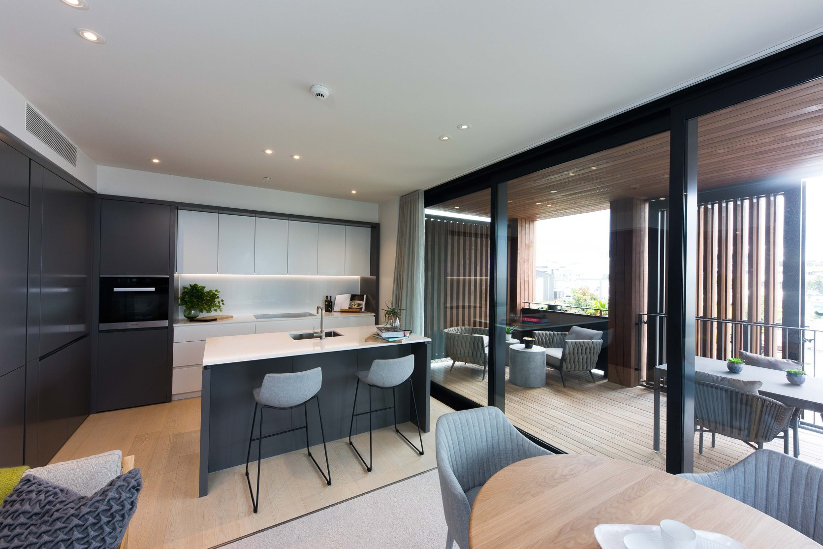 modern black and white kitchen, with large windows showcasing wooden exterior and deck area