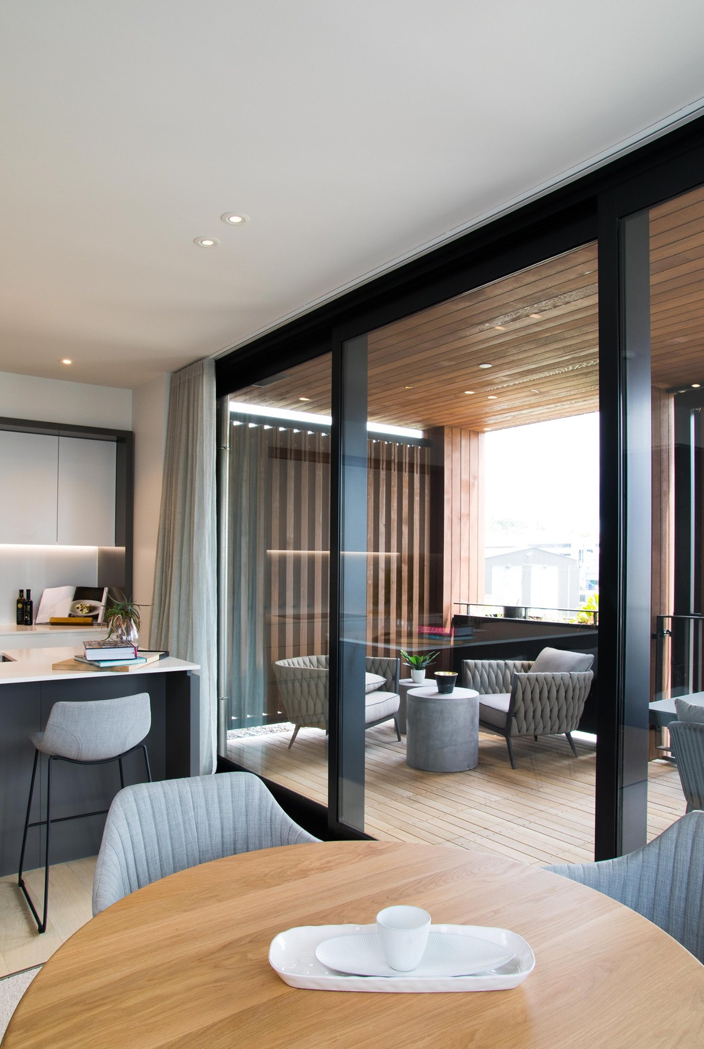 Contemporary kitchen in monochrome design, with expansive windows revealing the wooden exterior and decking