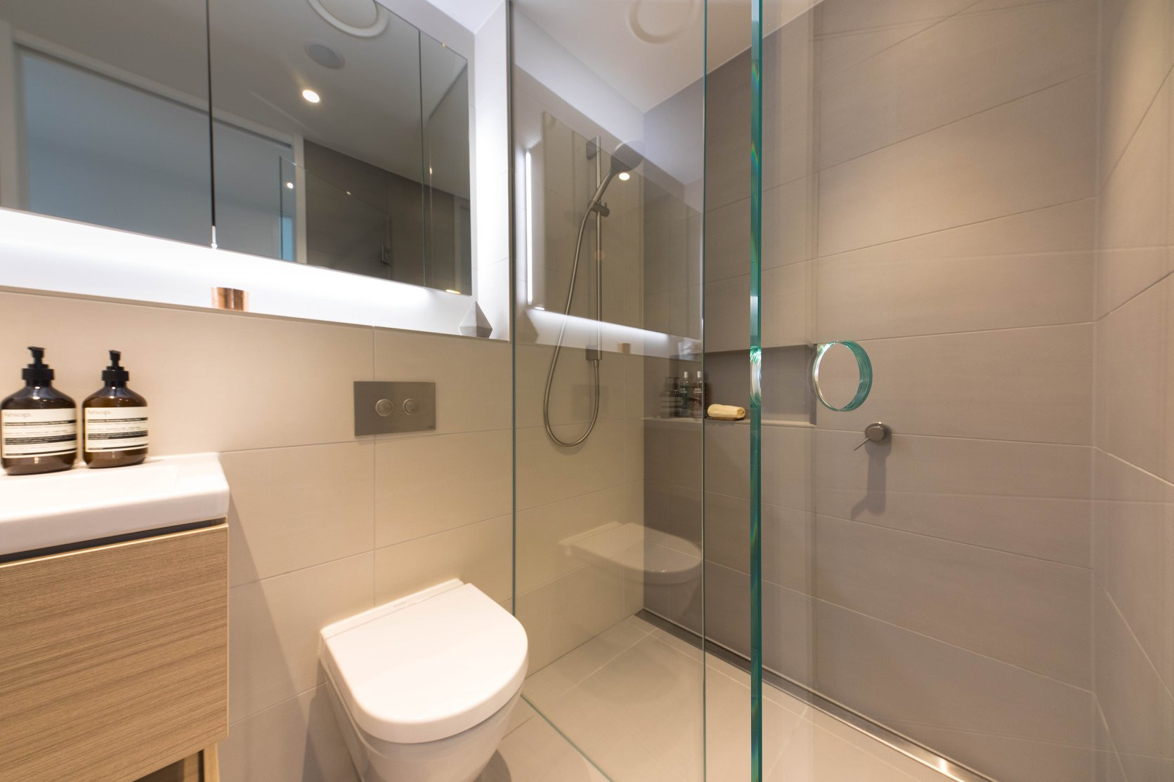 Contemporary bathroom design with a clear glass shower enclosure, toilet, and sink
