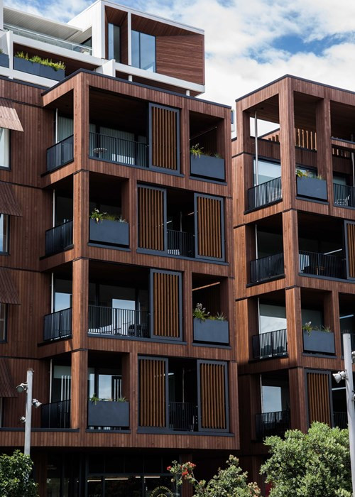 Wood-finished apartment building with glass balustrades and recessed balconies