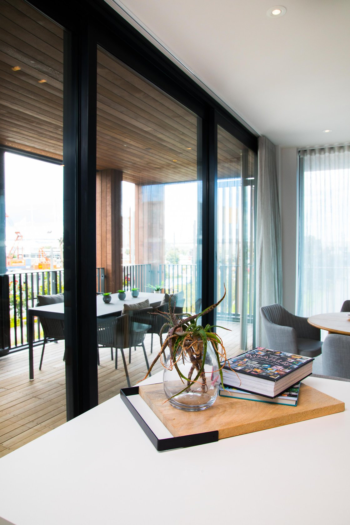 Interior dining area, featuring expansive windows that reveal a wooden exterior and decking