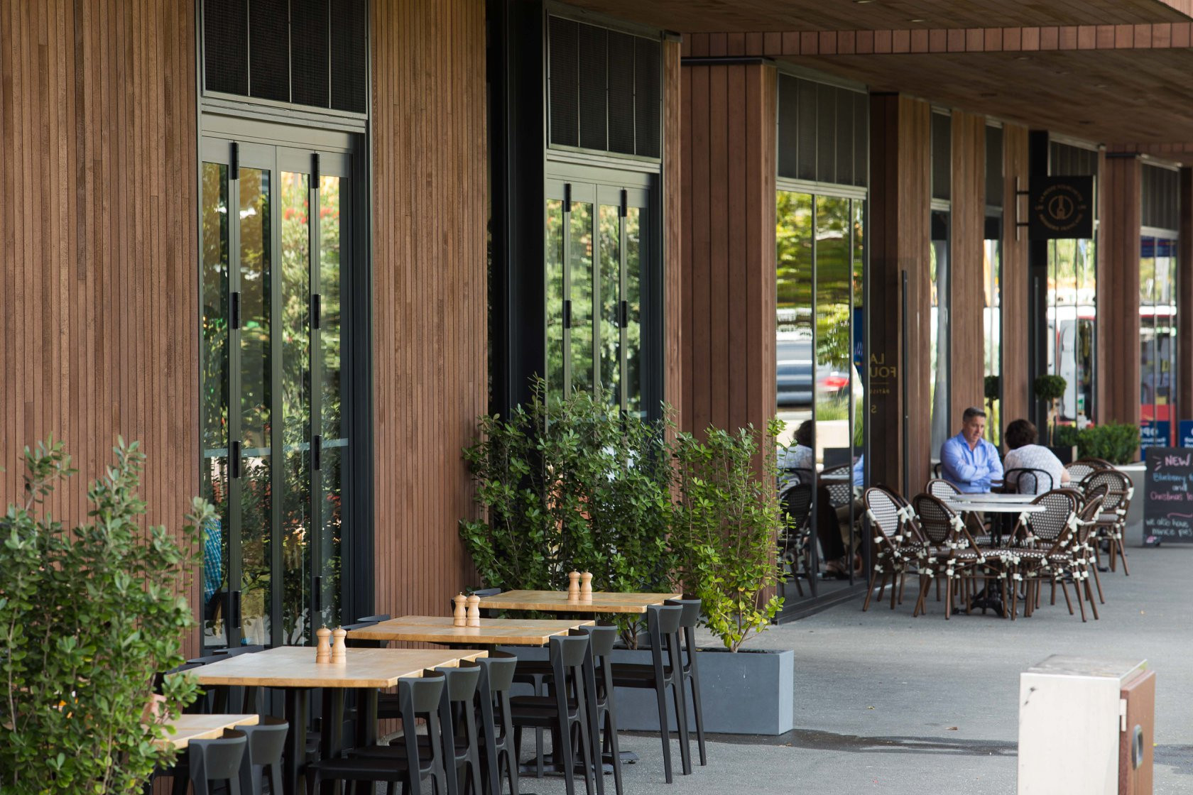 Building with a wooden facade and an outdoor café dining area