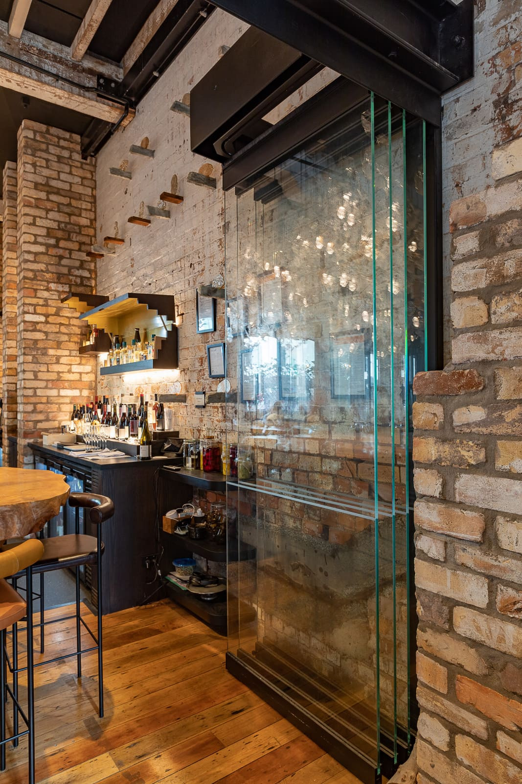 Image of a restaurant with a big glass wall and a huge table, situated in Britomart hotel with tall open windows