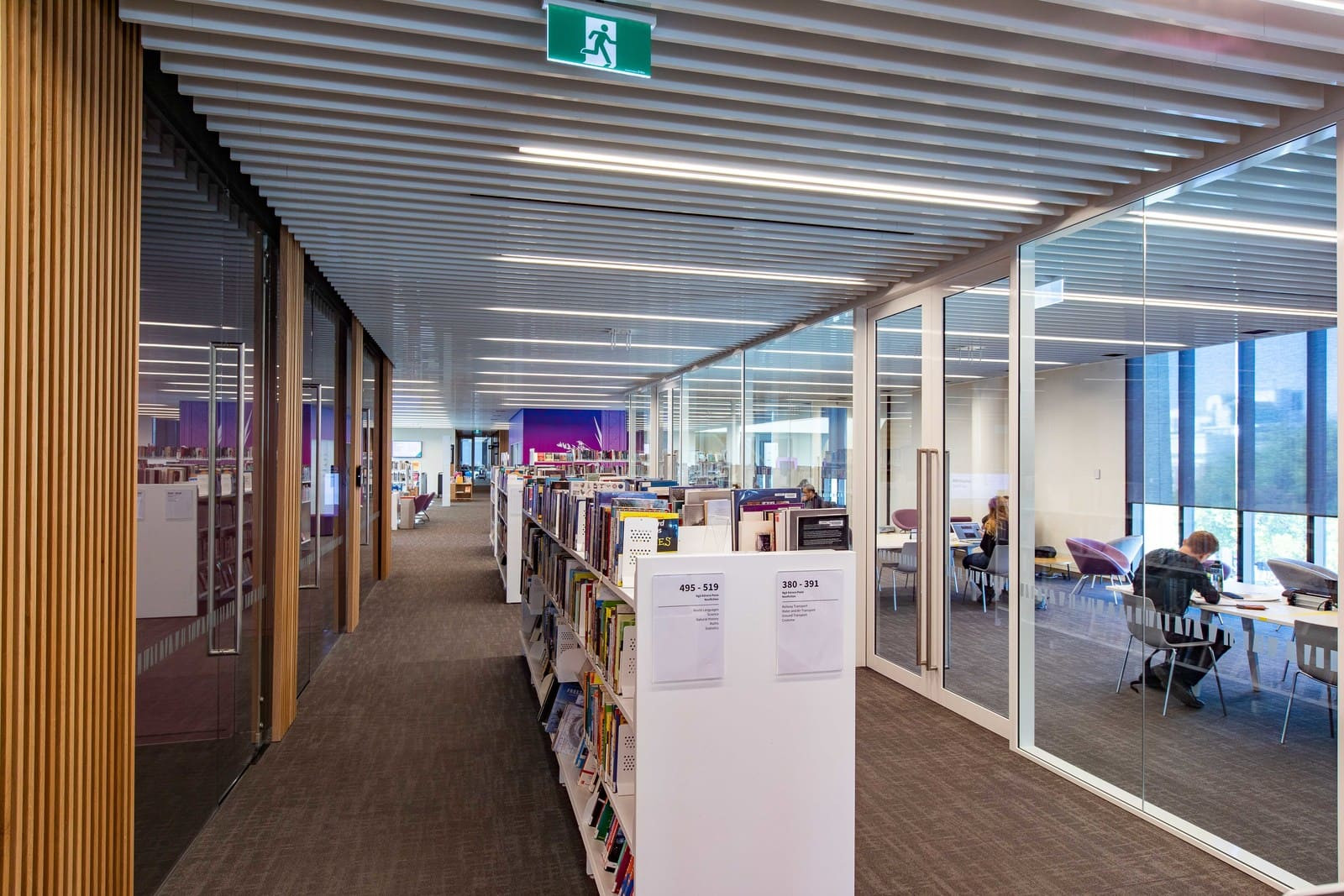 Modern library with glass doors, unique ceiling, and shelves full of books