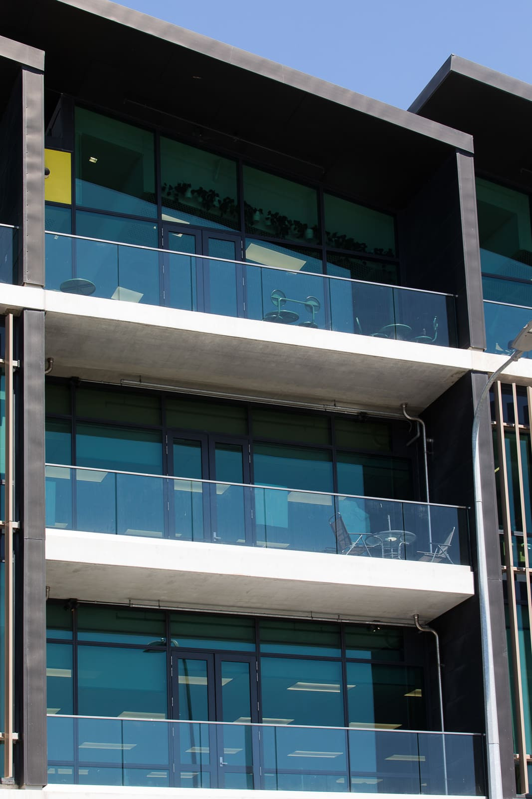 A modern building with a balcony and glass patterned exterior, highlighted panels on apartments