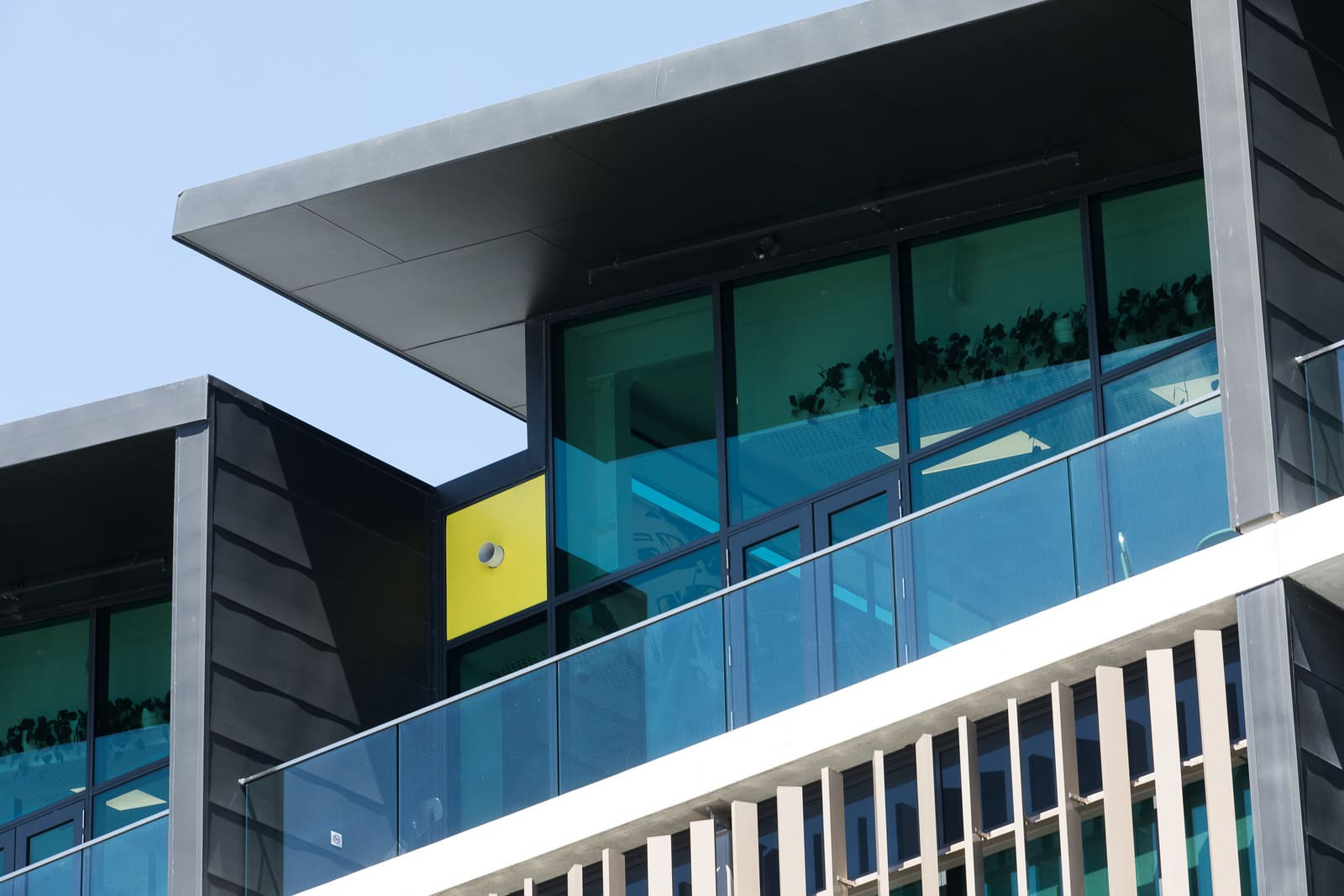 Modern structure with balcony, glass patterned exterior, highlighted panels on apartments