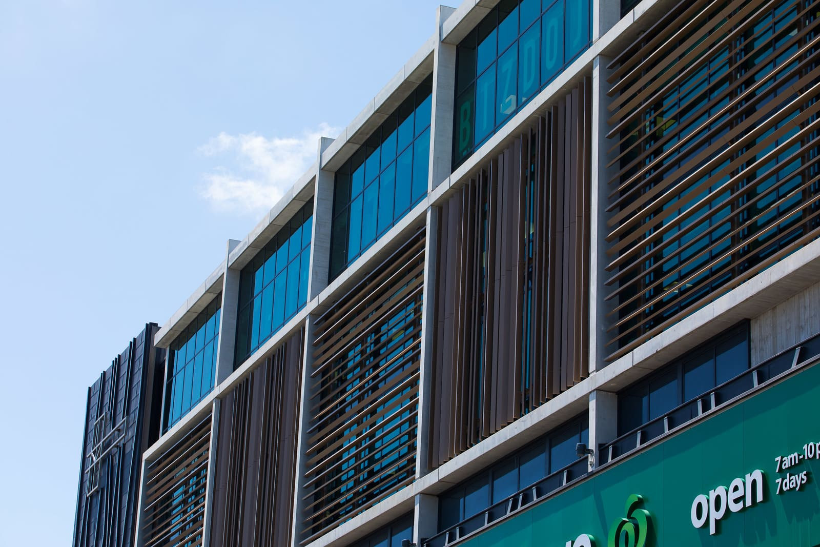 Building with balcony and glass patterned exterior, highlighted wooden panels on apartment facade