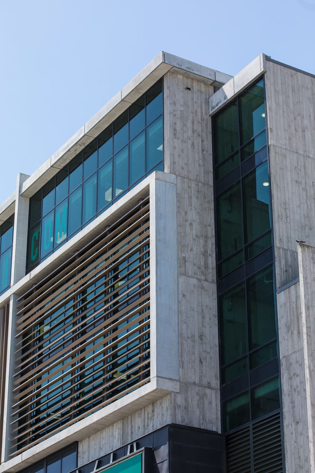 Modern structure with balcony, glass patterned exterior, highlighted wooden panels on apartments