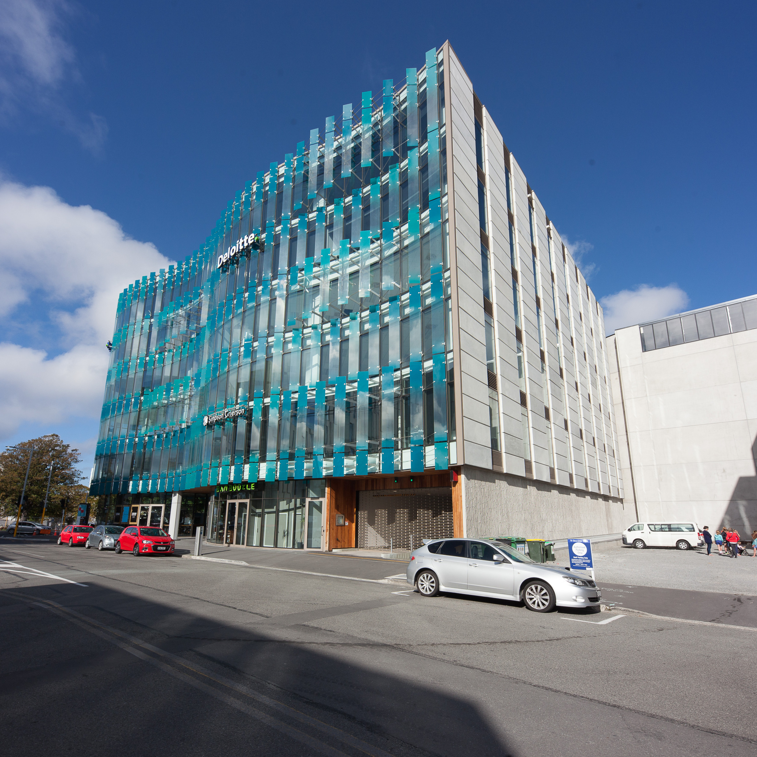 Urban building with a striking glass facade and highlighted detailing under clear blue skies