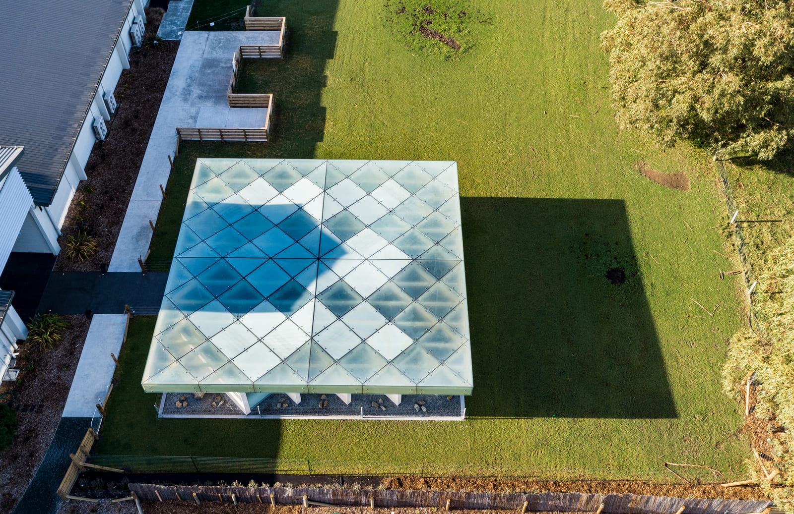 Looking down view through highlighted square patterned glass panels, surrounded by green grass