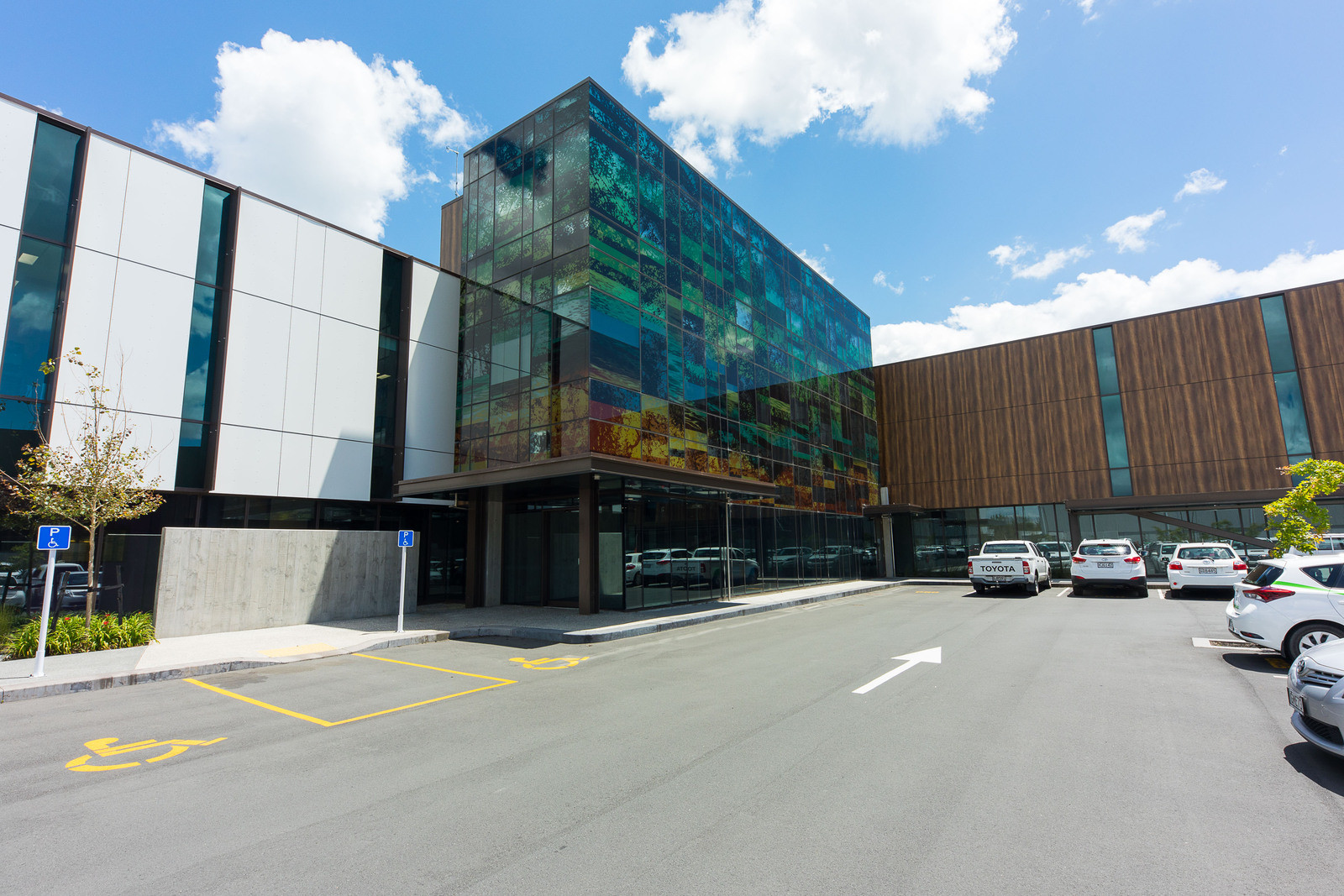 Large building with patterned glass exterior contrasting with wooden and white panels