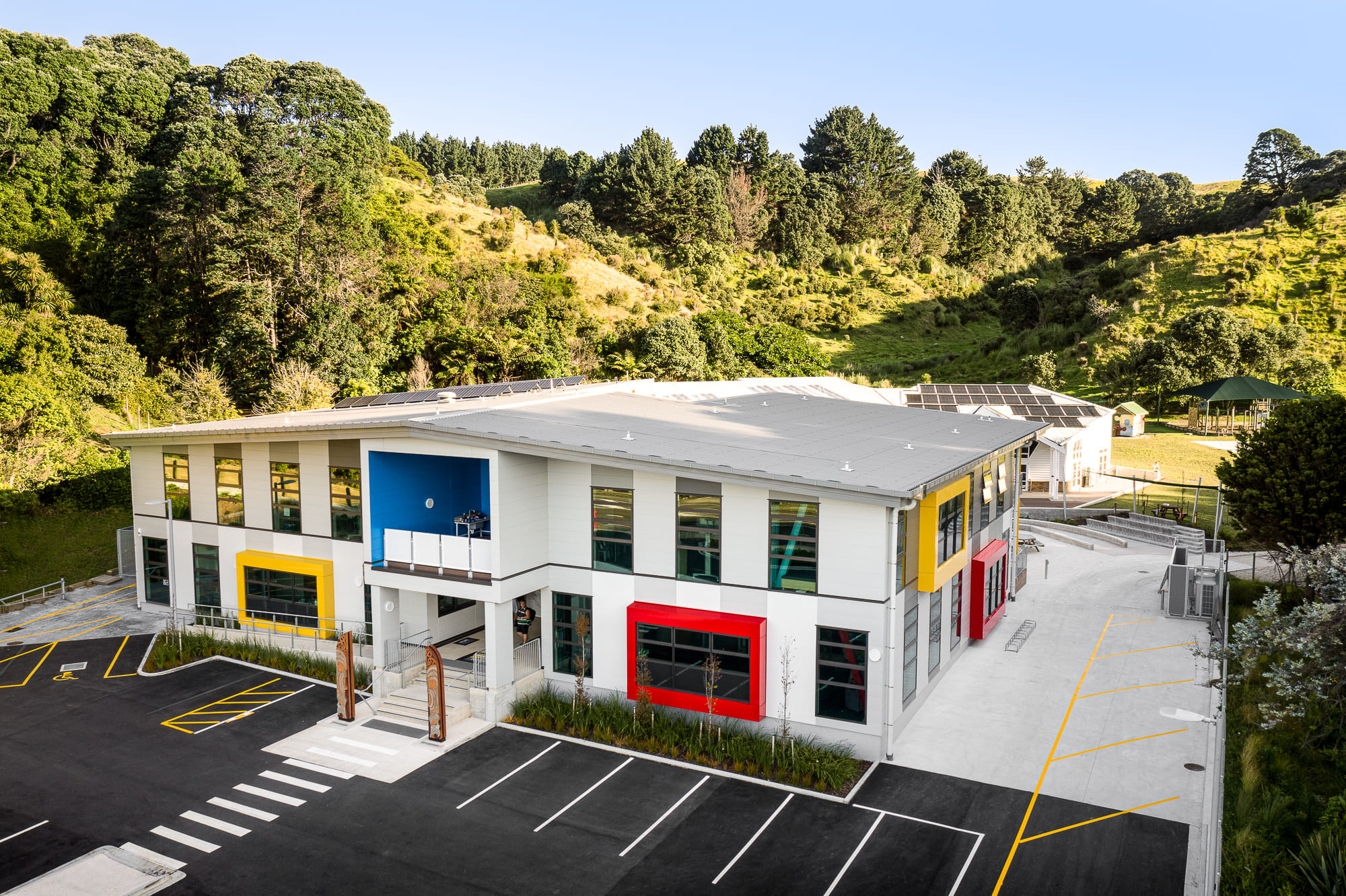 Colorful building with parking lot, Opope Beach School, featuring floor to ceiling windows