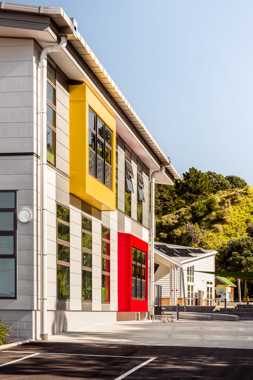 Multi-colored structure and parking lot at Opope Beach School, with tall windows