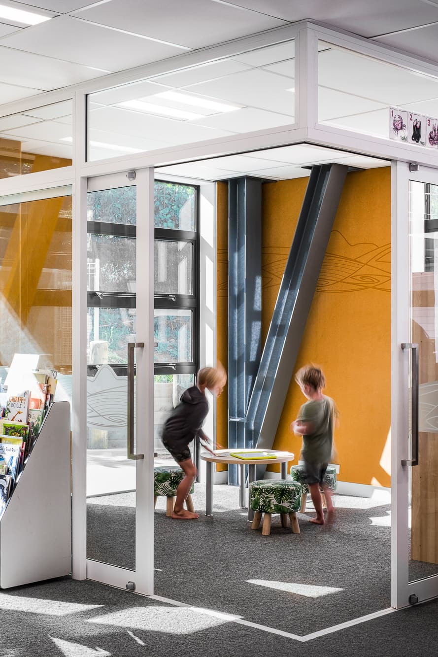 Kids playing in classroom with glass partition walls.