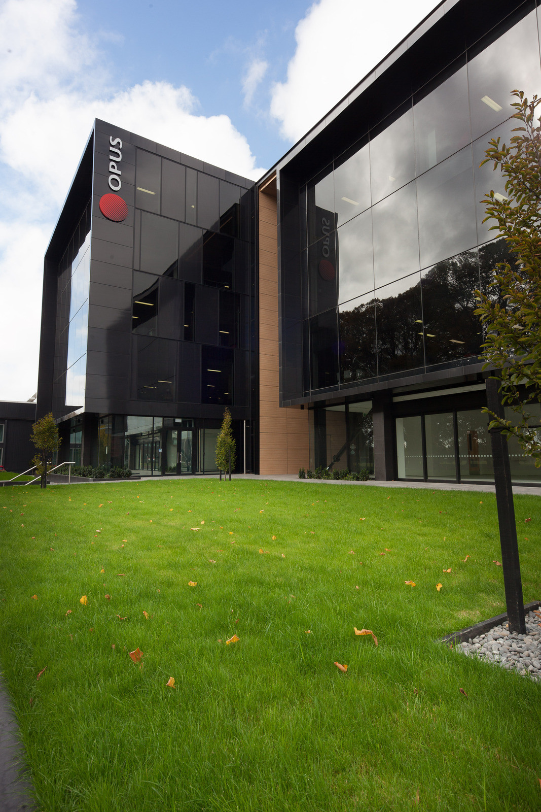 Opus building with dark tinted windows, set amidst lush green grass