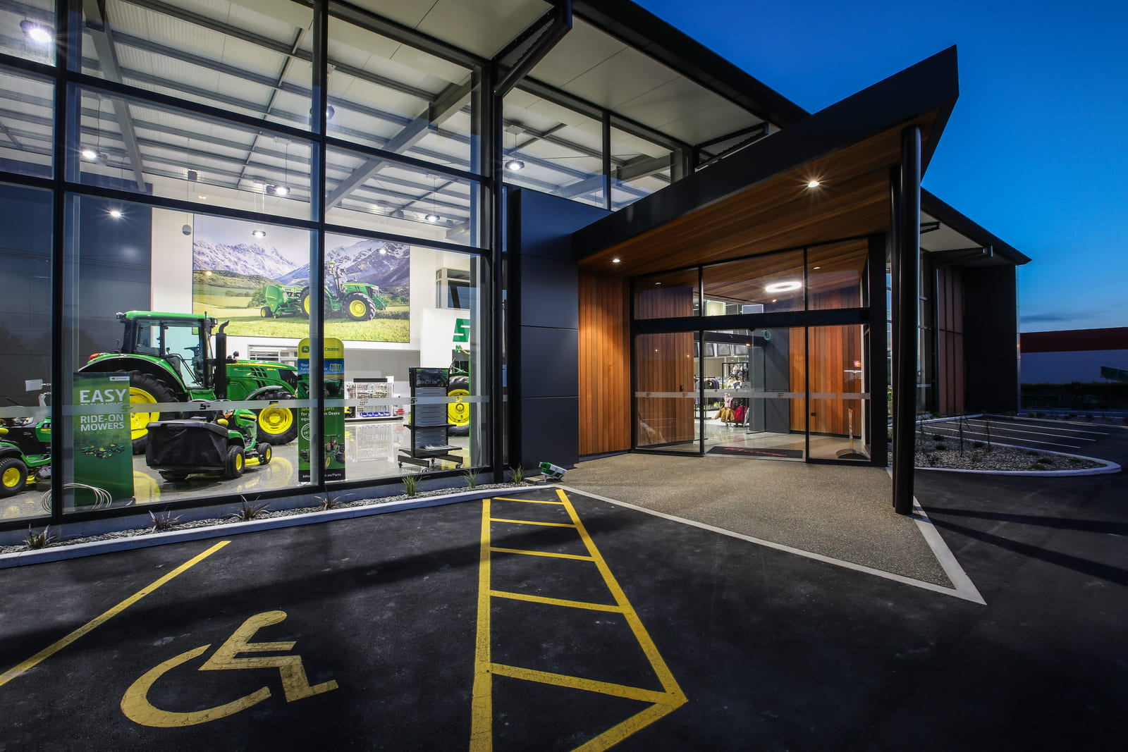 Brightly lit room with large glass windows displaying tractors