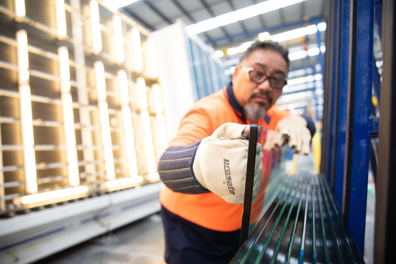 A worker in an orange shirt and safety glasses inspecting a Metro Glass Window.